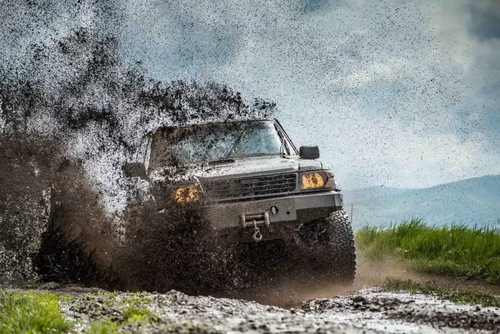 Geländewagen, der durch aufspritzenden Schlamm mit hoher Geschwindigkeit fährt. Auto Fotoshooting von Auto Fotograf Hannover.