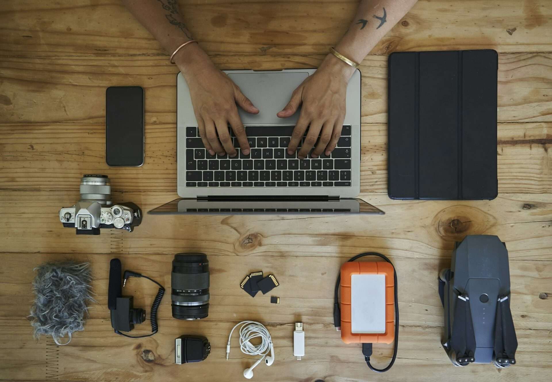 Person sitting at table with photografic equipment, using laptop, overhead view